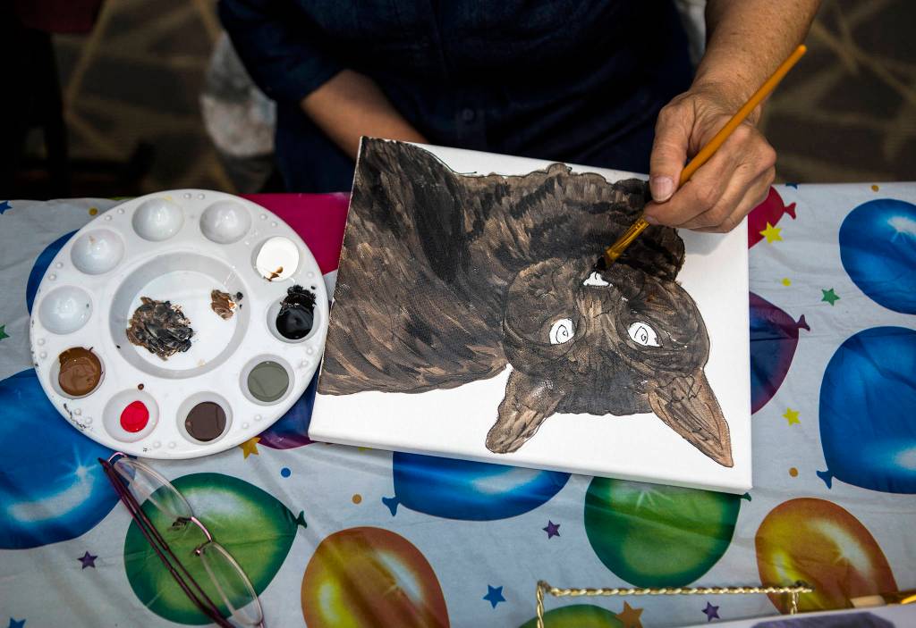 A painter works on a portrait of a shelter cat named Lilly during Shelter Pet Portraits at the Everett Mall on May 14. (Olivia Vanni / The Herald)