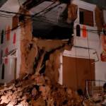 In this photo provided by Firefighters of Peru, people pass in front destroyed wall in Yurimaguas Peru, on Sunday. A powerful magnitude 8.0 earthquake struck the Amazon jungle in north-central Peru early Sunday, the U.S. Geological survey reported, collapsing buildings and knocking out power to some areas. (Firefighters of Peru via AP)