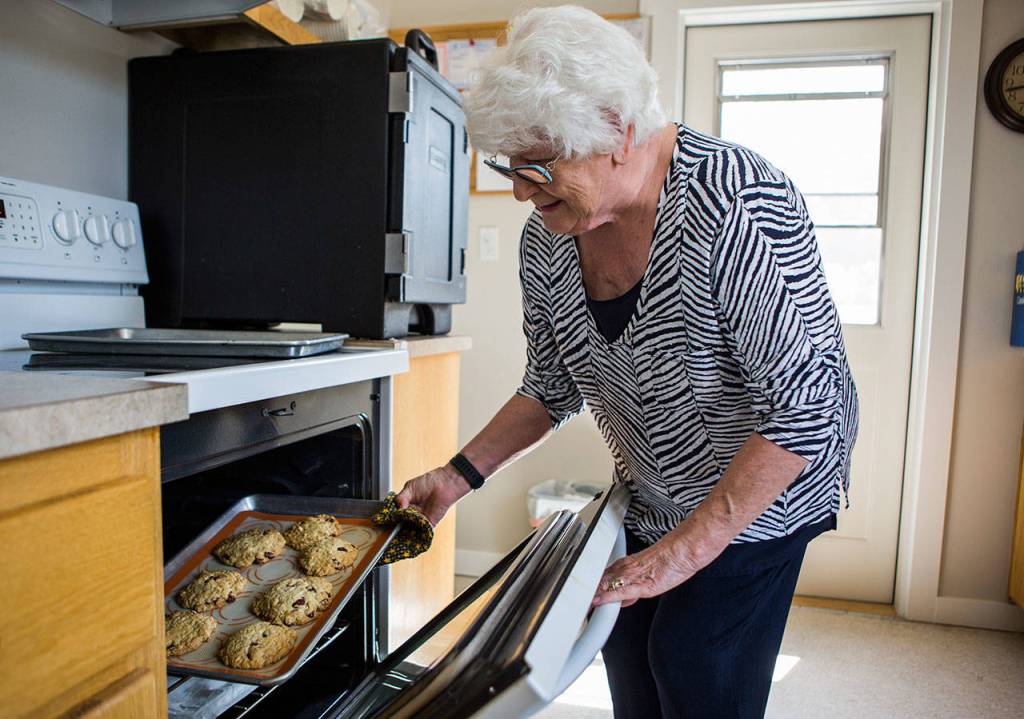 Mary-Margaret Haugen pulls a tray of cookies out of the oven at the Utsalady Ladies Aid building. (Olivia Vanni / The Herald)