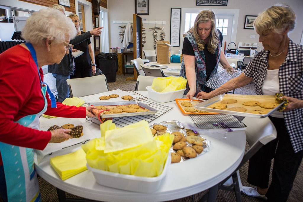 From left, Carol Kruse, Danielle Mickelson and Laurie Ware place trays of the groups freshly baked signature cookies on the table. (Olivia Vanni / The Herald)