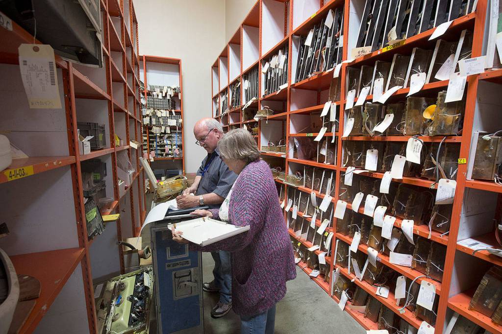 Lee Johnson and his wife, Lee Johnson, organize parts for oxygen boxes in a warehouse at Commercial Aircraft Interiors in Arlington. (Andy Bronson / The Herald)