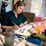 Elizabeth Person demonstrates some of the techniques she used while illustrating To Live on an Island at her in-home studio on May 22 in Everett. (Olivia Vanni / The Herald)