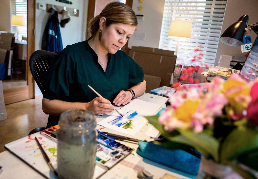 Elizabeth Person demonstrates some of the techniques she used while illustrating To Live on an Island at her in-home studio on May 22 in Everett. (Olivia Vanni / The Herald)