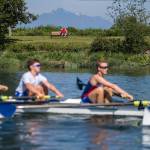 A man watches the Everett Rowing Associations varsity 8-plus-cox boat team with binoculars during a May 31 practice on the Snohomish River in Everett. (Olivia Vanni / The Herald)