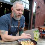 Owner J.P. Dowdell serves up a bowl of his favorite mac and cheese dish and a ginger mojito on the outside patio of Porters Public House in Langley. (Patricia Guthrie / Whidbey News Group)