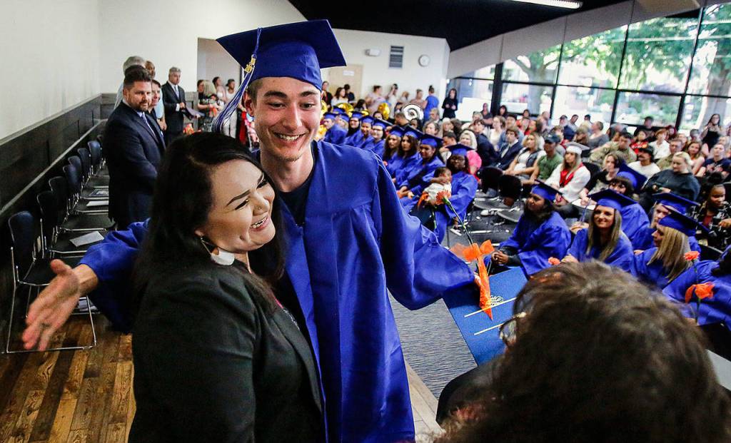 Robert Parkhurst opens his arms for case manager Amber Alvarez (left) and lead presenter and case manager Jennifer Pennycook as he picks up his documentation and generous hugs at Monday nights graduation ceremony. (Dan Bates / The Herald)