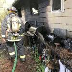 A firefighter evaluates the outside of a home after fire damaged it Monday morning in Lynnwood. (South Snohomish County Fire)