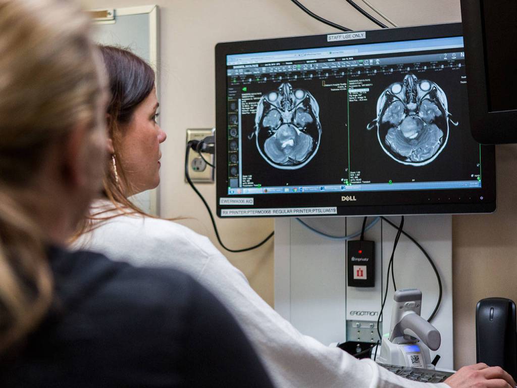 Susan Holtzclaw, ARNP, explains Kayas MRI brain scans to Jasmine at Seattle Childrens Hospital on Dec. 12, 2018. The scans show no measurable growth of Kayas brain tumor since she finished her radiation. (Olivia Vanni / The Herald)
