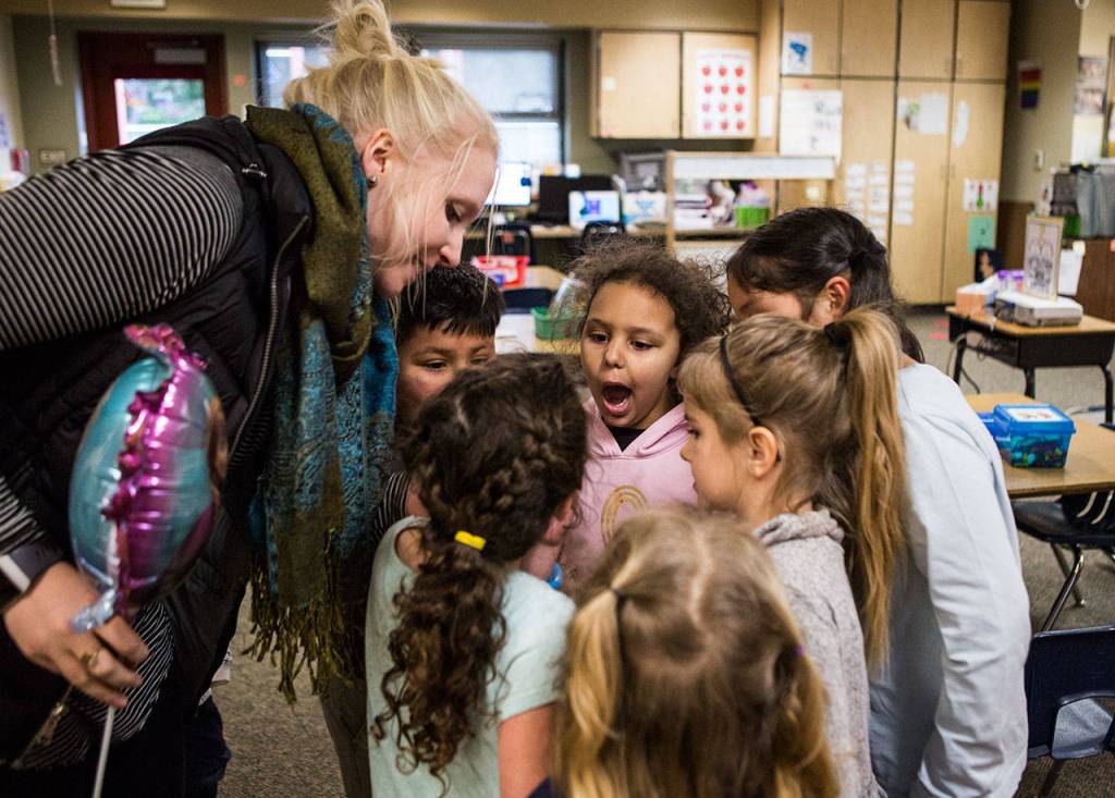 Kindergarten classmates stand around Kaya as she shows them where in her mouth she lost her first tooth during class at Emerson Elementary on Jan. 22. (Olivia Vanni / The Herald)