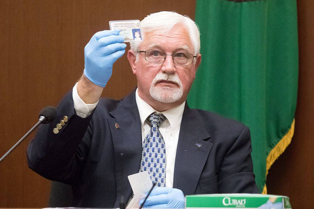 Retired Bellingham police Sgt. David Richards holds up the identification card of Tanya Van Cuylenborg during the trial for William Talbott II at the Snohomish County Courthouse on Friday in Everett. Richards found the cards behind Essies Tavern in Bellingham. Talbott is on trial for the double murder of Tanya Van Cuylenborg and Jay Cook. (Andy Bronson / The Herald)