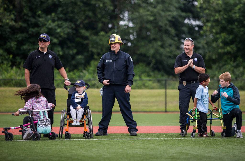 Monroe police officers and firefighters stand in the outfield with Charolette Wysocki, Isiah Kobernik and Edgerrin Burkett. (Olivia Vanni / The Herald)