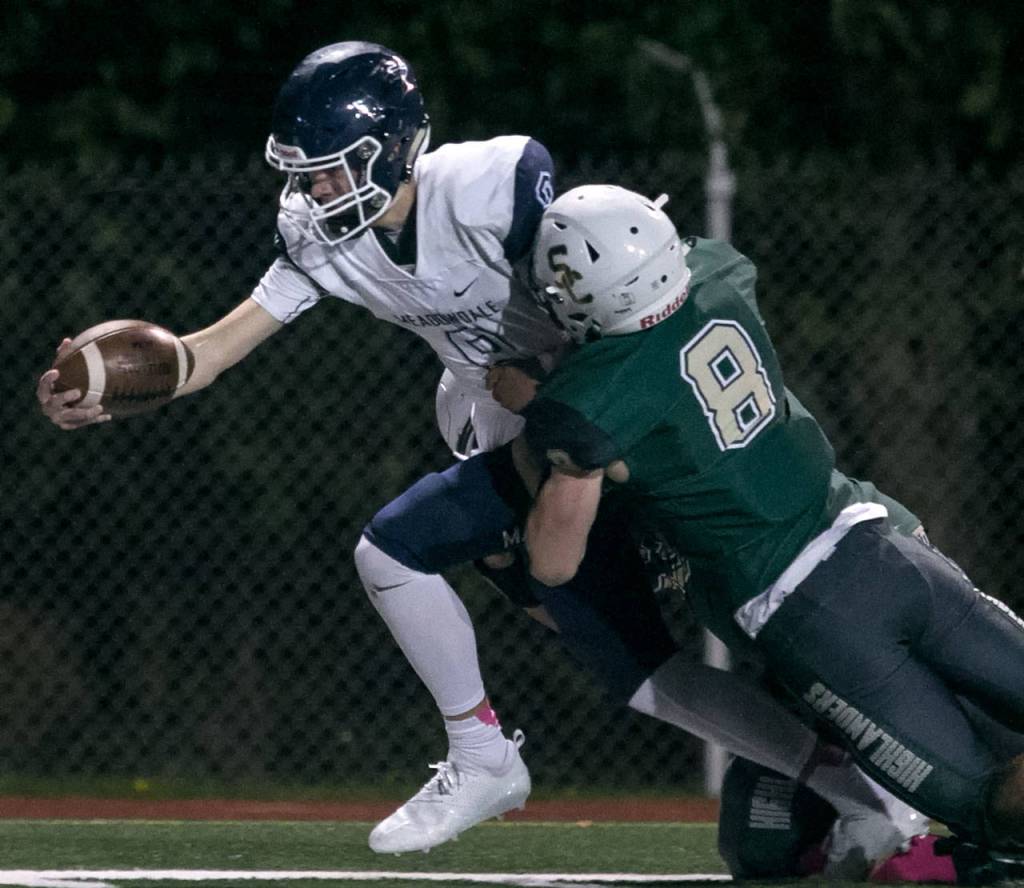 Meadowdales Hunter Moen reaches for extra yardage with Shorecrests Gavin McFarlane tackling at Shoreline Stadium on Oct. 12, 2018. (Kevin Clark / The Herald)