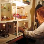 Shirley Viall adjusts furniture located in the kitchen of the miniature dollhouse created by Lyn DeShong. (Maria Matson / Whidbey News-Times)