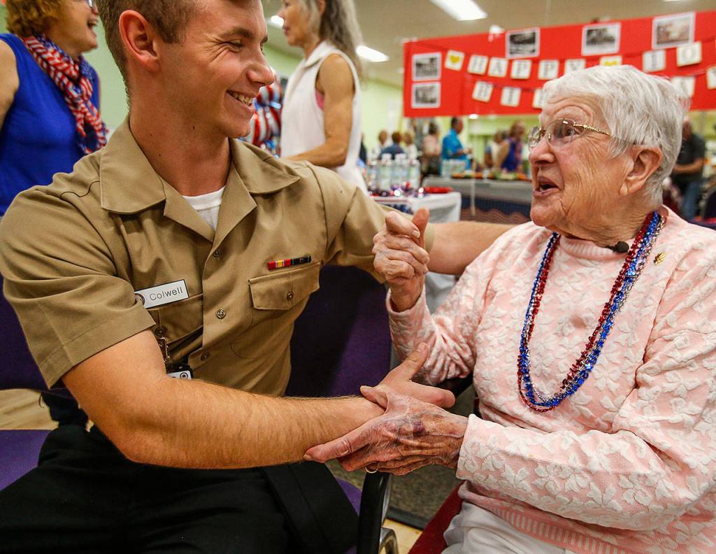 To the delight of her water aerobics pals, the 100-year-old birthday girl really enjoys the young sailors, including Corpsman Recruit Kristian Colwell from Naval Station Everett, attending the party. (Dan Bates / The Herald)