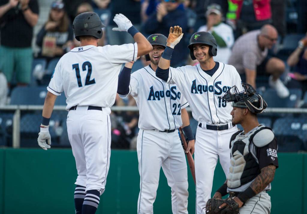The AquaSoxs Cash Gladfelter (12) gets high fives from teammates Carter Bins and Patrick Frick (right) after hitting a three-run homer during Everetts home opener against the Volcanoes on June 21, 2019, at Funko Field at Everett Memorial Stadium. (Andy Bronson / The Herald)