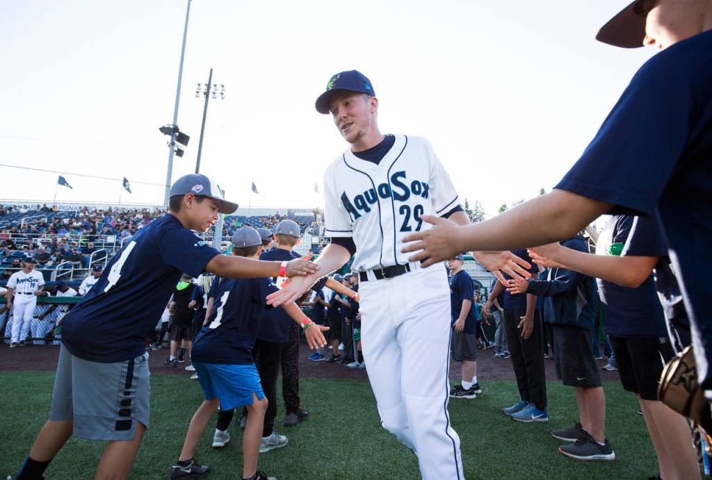 The AquaSoxs Tim Elliott get high fives as he is introduced before Everetts home opener against the Volcanoes on June 21, 2019, at Funko Field at Everett Memorial Stadium. (Andy Bronson / The Herald)