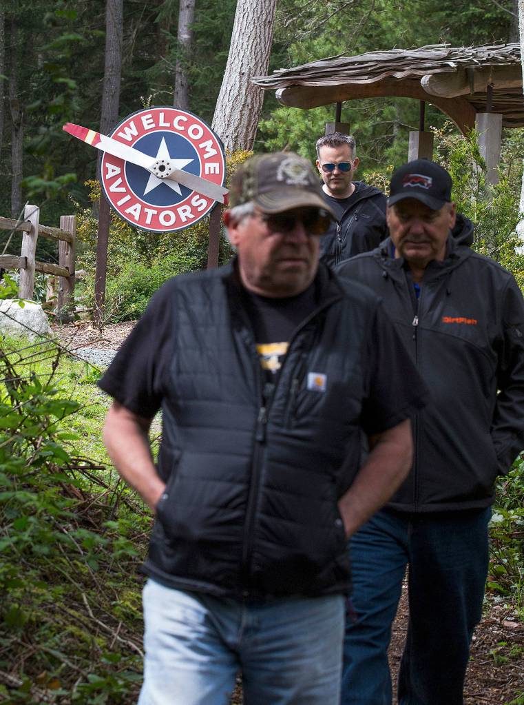 On their way back to their planes at Whidbey Airpark, Tarasievich, Todd Bohon and Kirk LeDoux pass by a Mukilteo Coffee Roasters sign welcoming aviators. (Andy Bronson / The Herald)