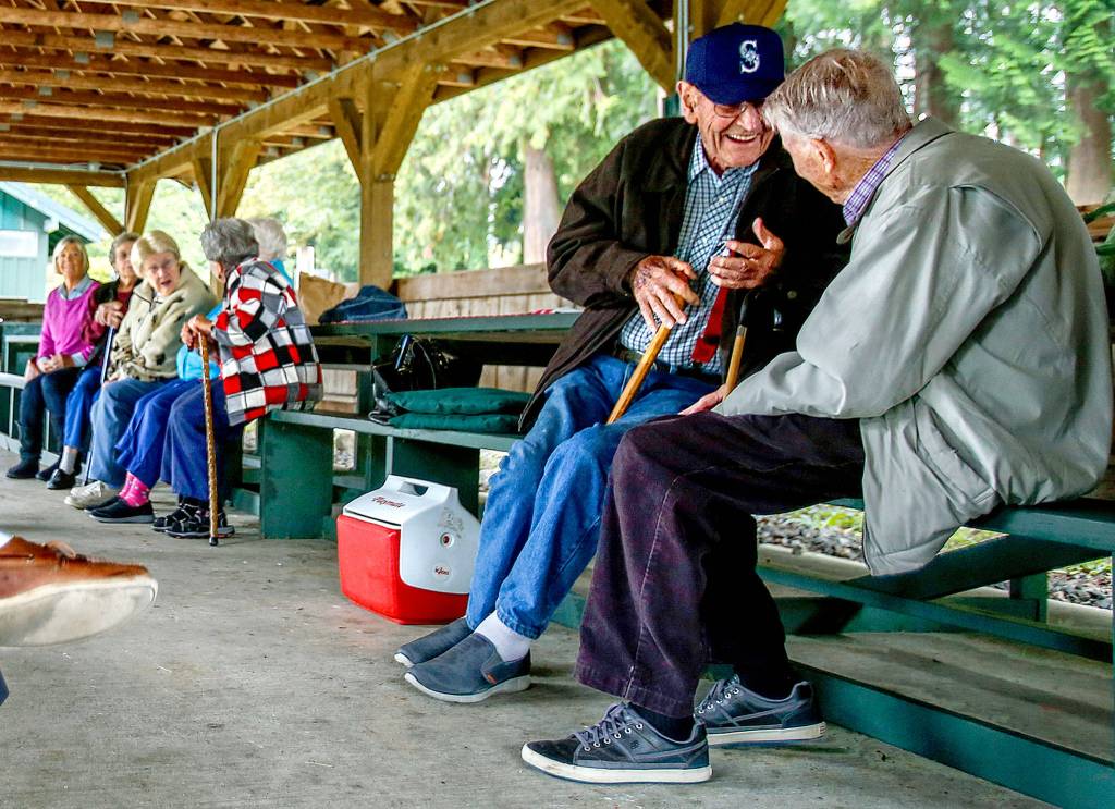 While some of the girlhood friends tell stories at a picnic table further down, Glen Allen (facing) bends the ear of Hugh Minor, 91, as the Snohomish High School class of 1942 meets at Hill Park to have lunch and visit during a lively annual class reunion. (Dan Bates / The Herald)