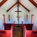 A white interior with four red pews at the Wayside Chapel on U.S. 2. (Olivia Vanni / The Herald)