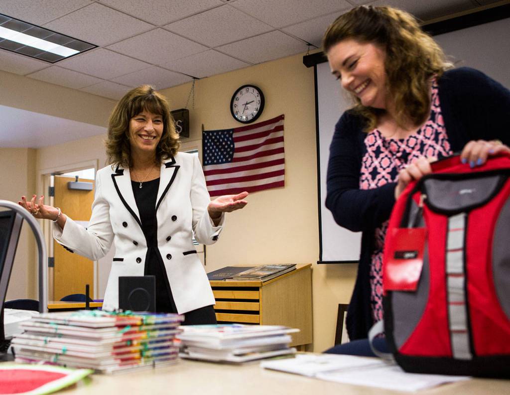 Alysia White (right) a seventh- and eighth-grade English teacher laughs as Joyce Stewart reacts to her goodbye gift in June at Evergreen Middle School in Everett. Stewart worked for the Everett School District for 20 years, including 12 years as a principal and eight more at the district administration office. She retires Wednesday. (Olivia Vanni / The Herald)