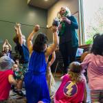 Kids, some clad in superhero costumes, dance to a rocket-themed song played by Shannon Horrocks at the library. (Olivia Vanni / The Herald)