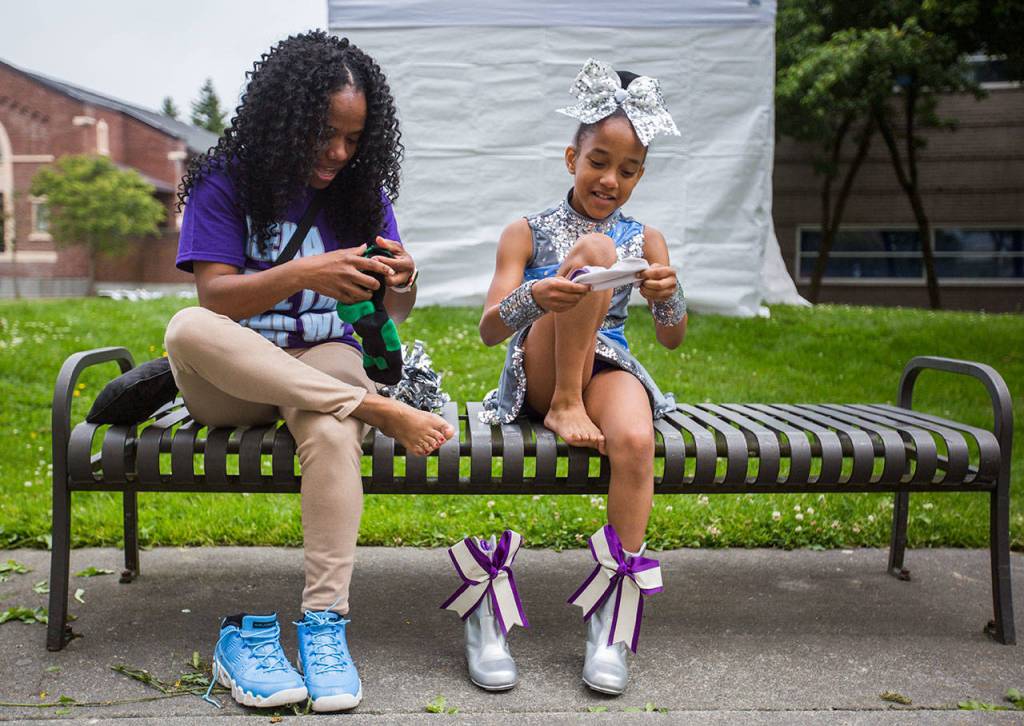 Shameca Orton, left, trades socks with her daughter Jaedyn Orton, 10, so she wont get blisters from her drill shoes during the Colors of Freedom Fourth of July Parade on Thursday, July 4, 2019 in Everett, Wash. (Olivia Vanni / The Herald)