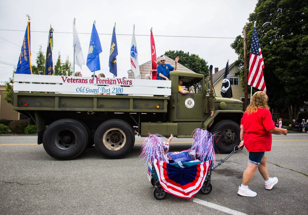 Members of the Veterans of Foreign Wars float wave at Makena Kombol as she passes by in her wagon during the Colors of Freedom Fourth of July Parade on Thursday, July 4, 2019 in Everett, Wash. (Olivia Vanni / The Herald)