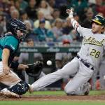 The Athletics Matt Olson (28) scores as Mariners catcher Tom Murphy catches the throw during the seventh inning of a game on July 5, 2019, in Seattle. (AP Photo/Elaine Thompson)