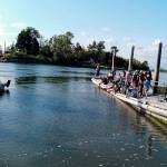 A small crowd (right) gathered Saturday at Langus Park on the Snohomish River for a short preview of the Flotsam River Circus. They are watching performers aboard the hand-built vessel that Everett musician Jason Webley plans to float on Oregons Willamette River, from Corvallis to Portland, presenting free shows along the way. (Photo by Michael Jepson)