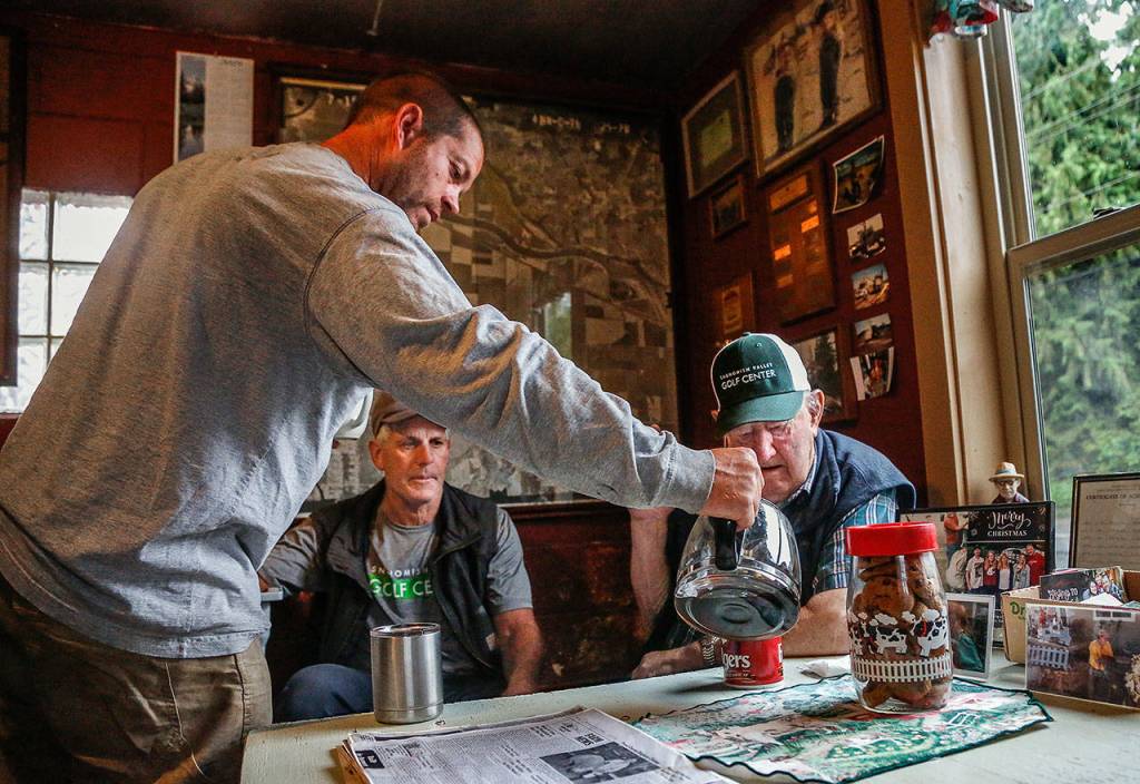 In a small room where friends drop by every morning except Sunday, TJ Stocker, 38, refills Bill Cravens coffee early Wednesday. TJs dad, Tim Stocker, 61, (back) watches. (Dan Bates / The Herald)