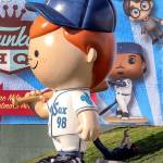 A fan rests in the shadow of the Freddy Funko statue on Funko Friday at Funko Field in Everett on July 12, 2019. (Kevin Clark / The Herald)