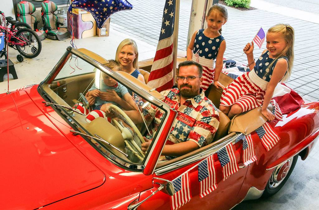 Olaf Wecker of Seattle offered up his red 1958 Mercedes 190SL convertible for the mayors parade car in the Edmonds 4th of July parade. He is posed here with his wife, Christy, holding Walter, Karolin (left back) and Katrin (far right). (Kevin Clark / The Herald)