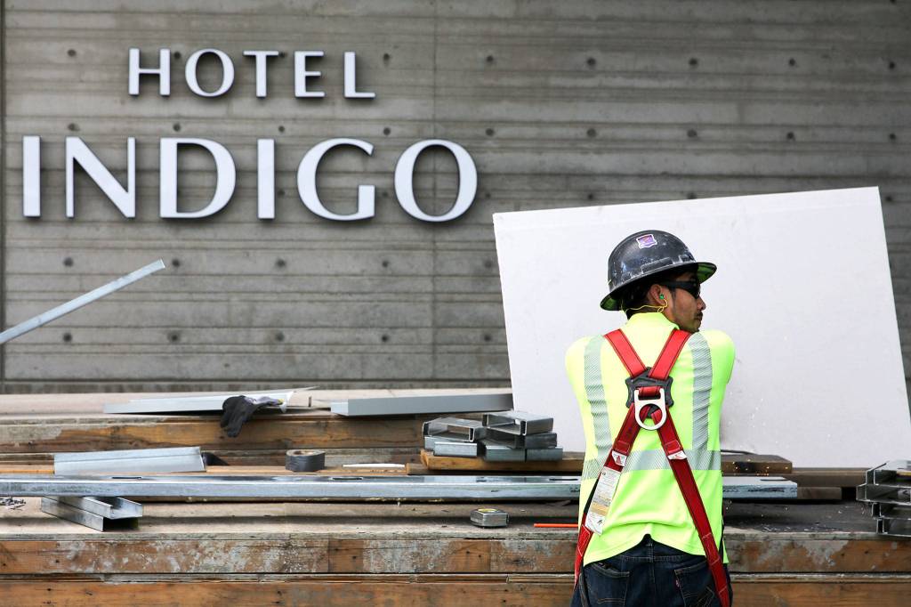 A construction crew member cuts steel at Hotel Indigo during construction on Port of Everetts Waterfront Place on June 26. (Kevin Clark / The Herald)