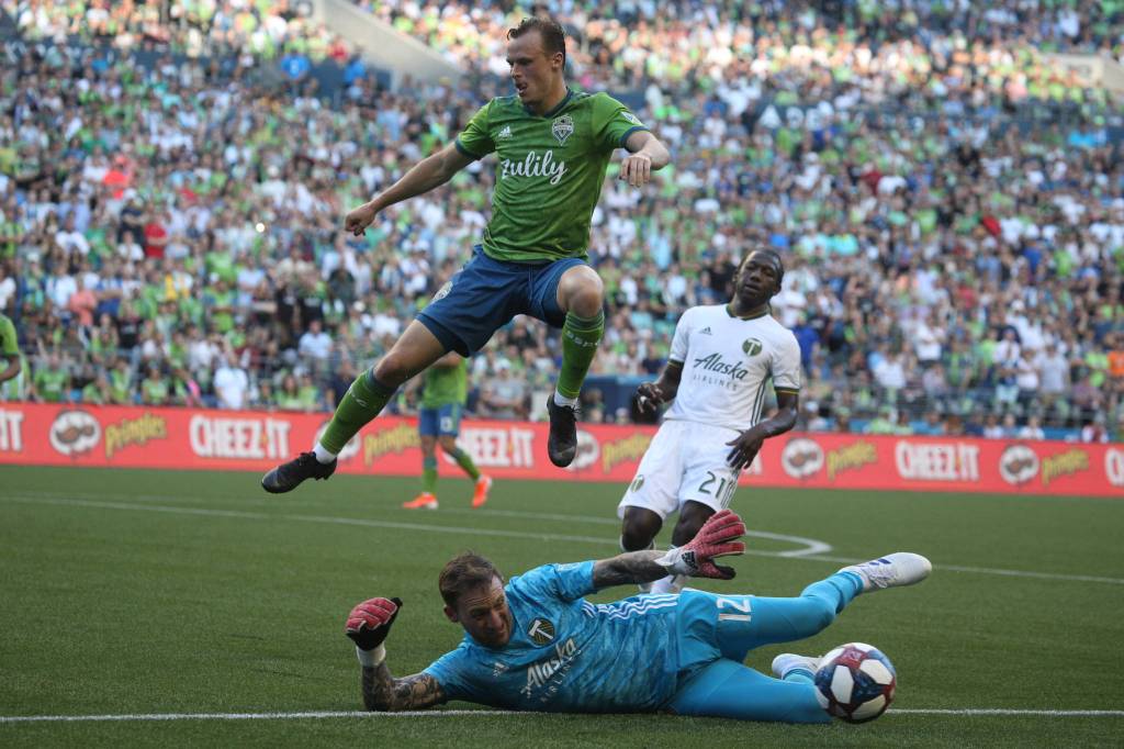 Seattles Brad Smith leaps over a sliding Steve Clark as the Seattle Sounders lost 2-1 to the Portland Timbers at CenturyLink Field on Sunday, July 21, 2019 in Seattle, Wash. (Andy Bronson / The Herald)