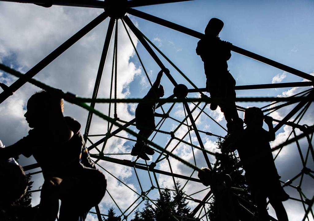 Children climb on the new rope structure at the re-opening of Seaview Parks playground Wednesday in Edmonds. (Olivia Vanni / The Herald)