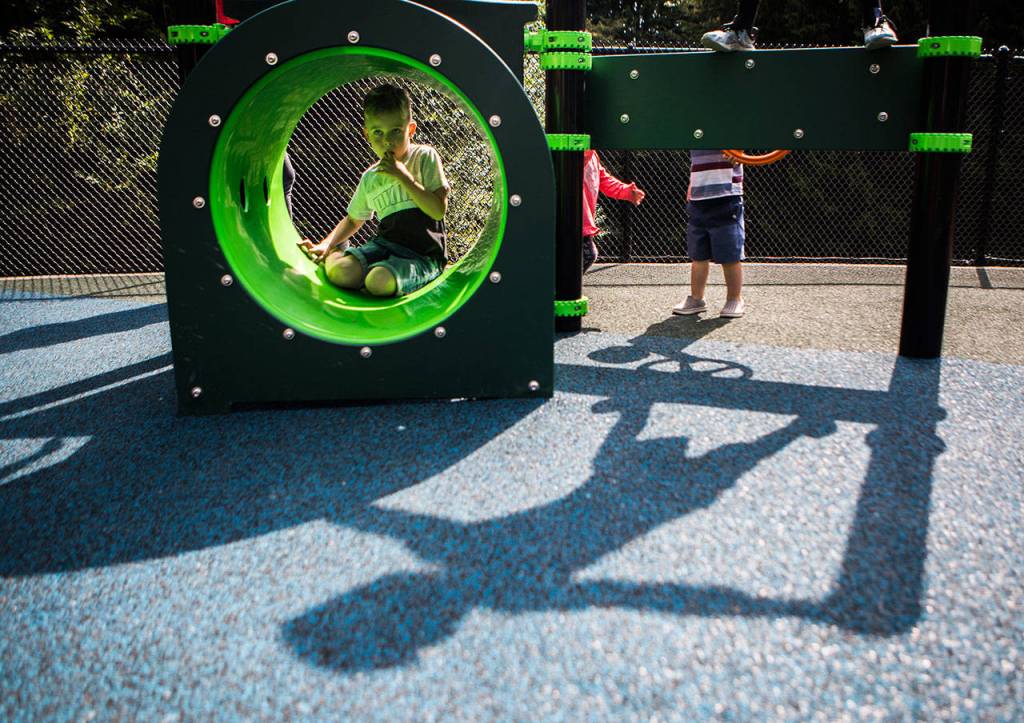 Children climb atop and through one of the new inclusive-style playground structures at the re-opening of Seaview Parks playground Wednesday in Edmonds. (Olivia Vanni / The Herald)