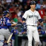 The Mariners Dylan Moore tosses aside his bat after striking out as Rangers catcher Tim Federowicz heads to the dugout at the end of the fifth inning of a game on July 23, 2019, in Seattle. (AP Photo/Elaine Thompson)