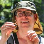 Rich Schleifer examines swag from the GCD geocache on Mount Margaret. (Kevin Clark / The Herald)