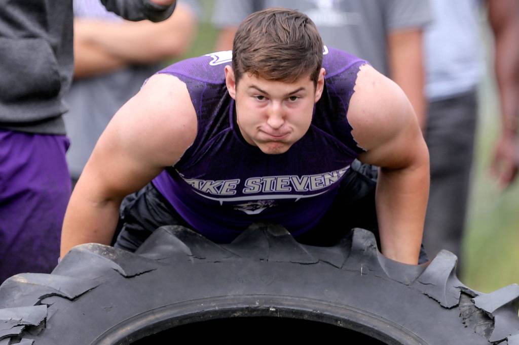 Lake Stevens Wyatt Hall races in the tire-flip relay as part of the lineman challenge. (Kevin Clark / The Herald)
