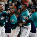 The Mariners Mallex Smith (second from left) is mobbed by teammates, including J.P. Crawford (left), Tim Beckham (second from right), and Omar Narvaez (right) after Smith hit a walk-off RBI single in the ninth inning of a game against the Tigers on July 26, 2019, in Seattle. (AP Photo/Ted S. Warren)