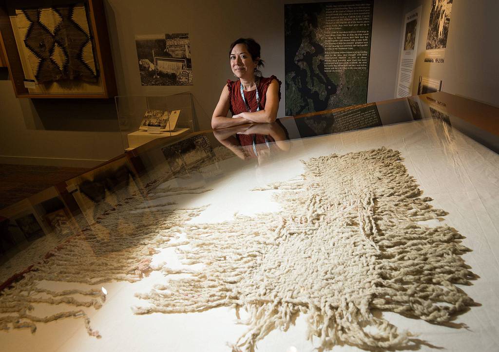 Senior curator Tessa Campbell poses with a rare example of a blanket made from woolly dog hair and mountain goat hair at the Hibulb Cultural Center on July 22 in Tulalip. (Andy Bronson / The Herald)