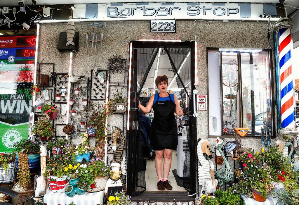 Flowers, faux sea creatures and other decor line the exterior of the Barber Stop in Everett as owner Brenda Humbert welcomes a visitor. (Dan Bates / The Herald)