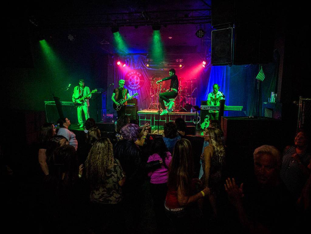 Frontman Michael Henrichsen, center, leaps across the stage as 80s fans dance to Nite Waves show at Tony Vs Garage in Everett. (Olivia Vanni / The Herald)