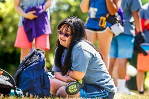 After arriving at Camp Prov in Forest Park on Wednesday, volunteer Bre Baylon sits down on the dry grass and enjoys the sights around her. Shes a former camper in the program for children with special needs. (Dan Bates / The Herald)