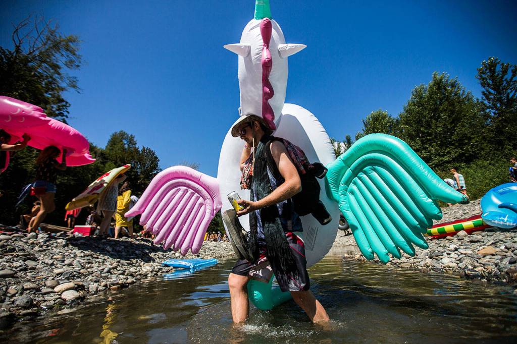 A unicorn float toy is carried across the river at the festival, which takes place amid mountain wilderness in Darrington. (Olivia Vanni / The Herald)