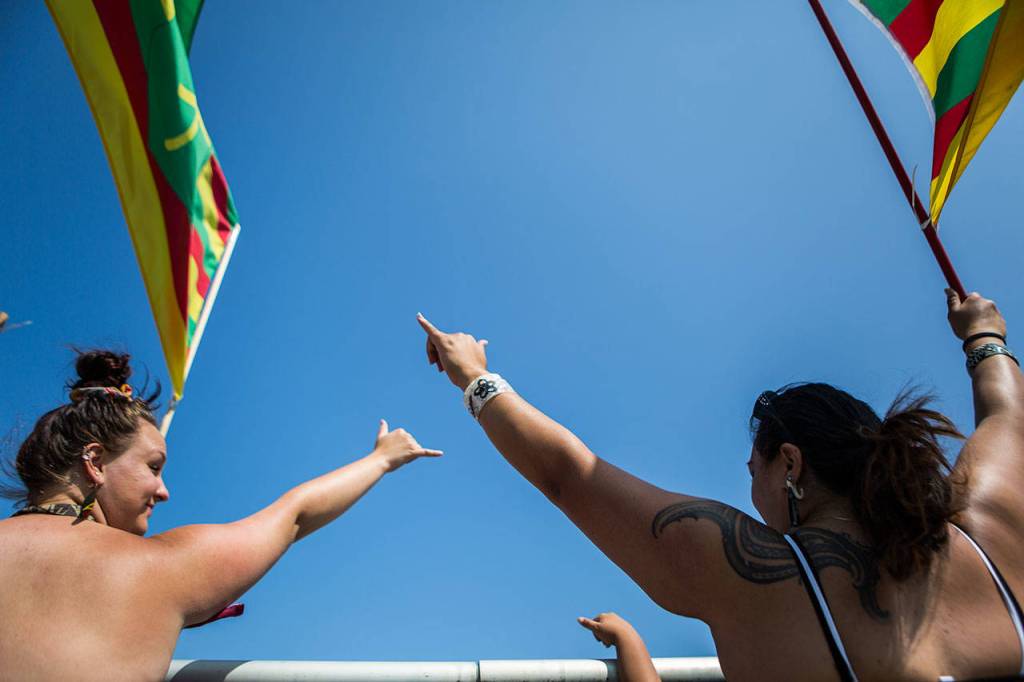 Protestors wave shaka signs to drivers that honk during their demonstration on the I-5 overpass on Saturday in Marysville. (Olivia Vanni / The Herald)