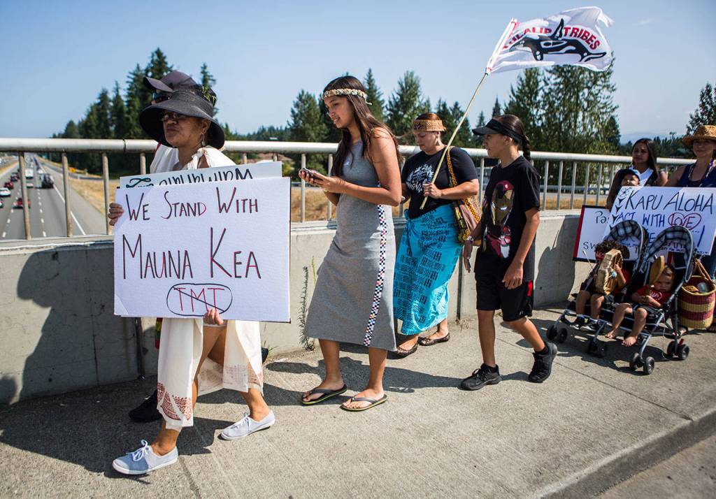 People make their way across the I-5 overpass singing, chanting and carrying signs and flags Saturday in Marysville. (Olivia Vanni / The Herald)