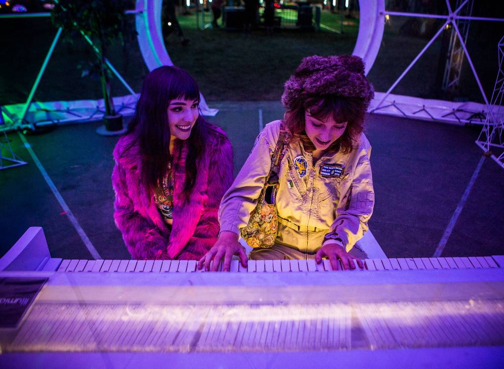 Olivia Cleven, left, smiles at Emma Brooks, right as she plays the piano in The Sensatorium art installation during the first day of Summer Meltdown on Thursday, Aug. 1, 2019 in Darrington, Wash. (Olivia Vanni / The Herald)