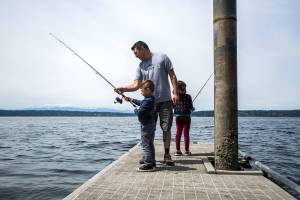 Gino Sanita, center, teaches his son Carlo Sanita, 5, left, and daughter Virgina Sanita, 7, how to fish off of the boat launch dock at Camano Island State Park. (Olivia Vanni / The Herald)