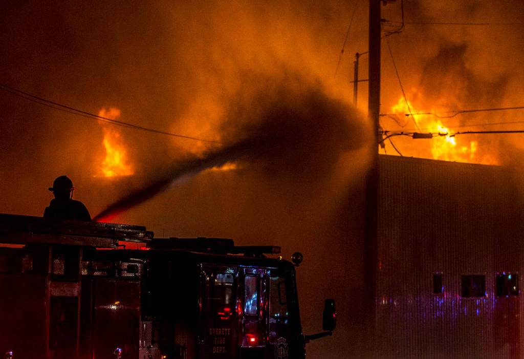 A Everett firefighter sprays water on the Judd & Black appliance store that burned on Sept. 21, 2018 in Everett. (Olivia Vanni / Herald file)